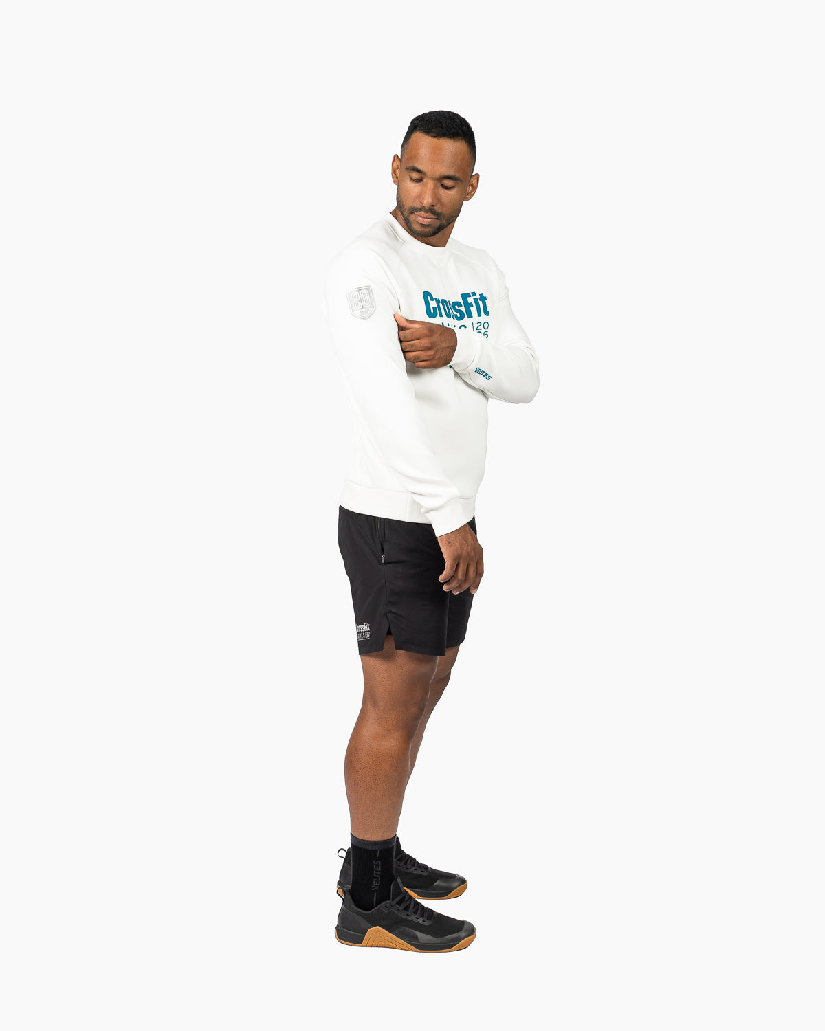Side profile view of the unisex pearl white crewneck sweatshirt styled with training shorts