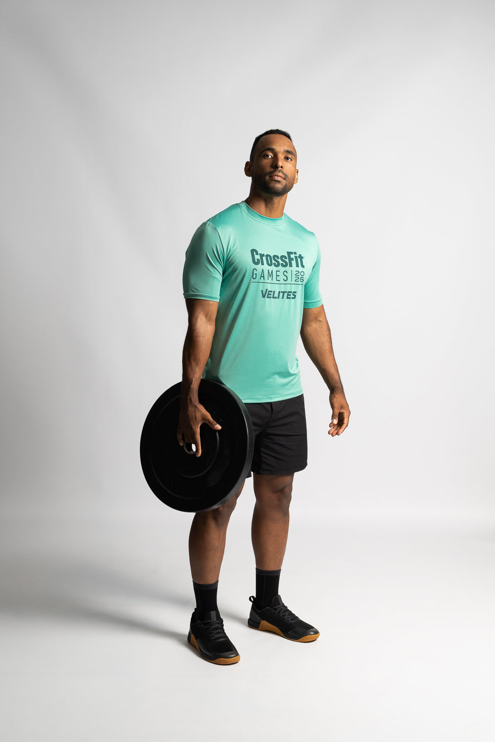 Athlete holding a bumper weight plate wearing the CrossFit Games capsule collection training tee