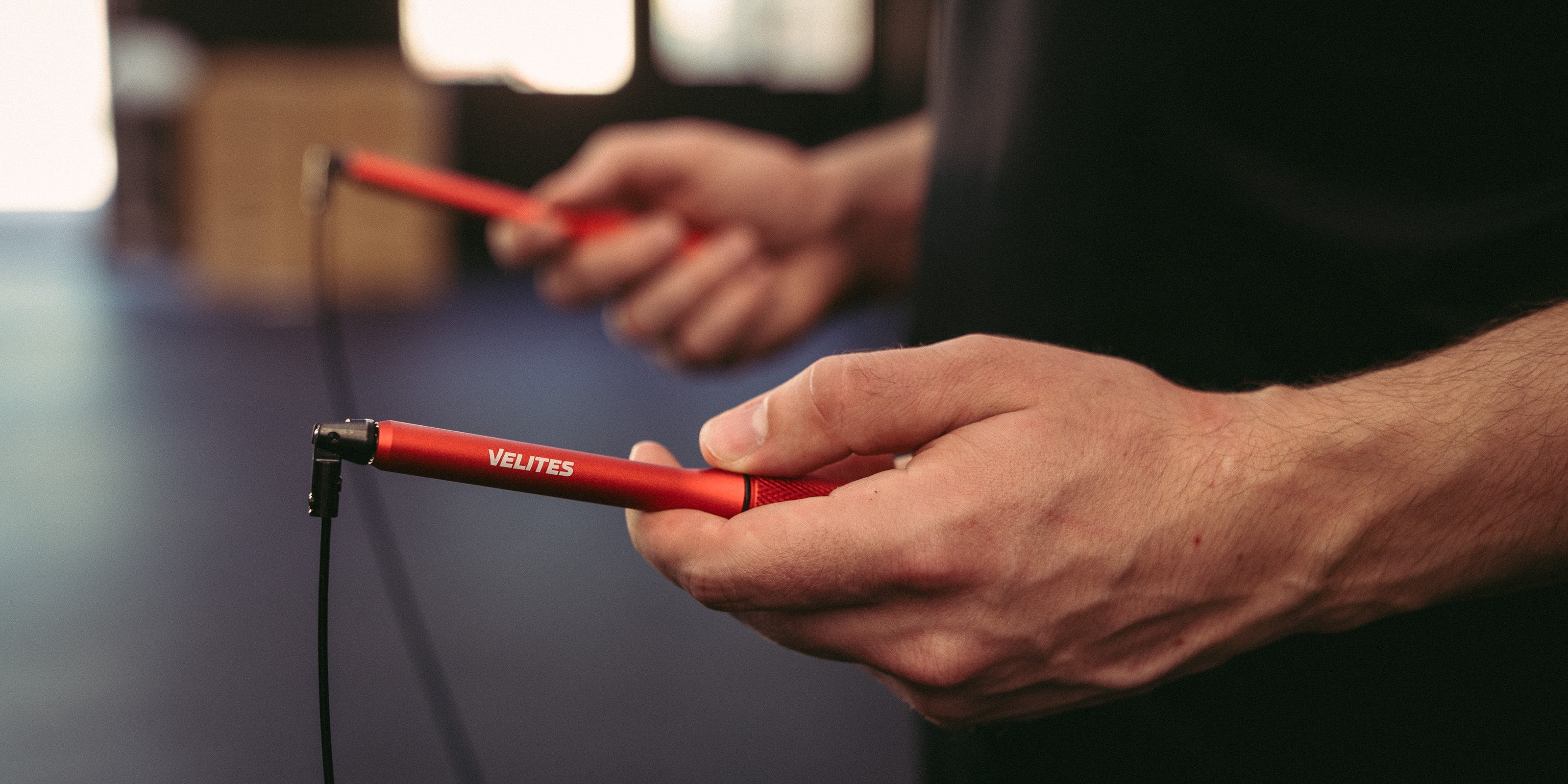 Close-up of Velites red jump rope handles held by an athlete – premium speed rope for CrossFit, boxing, and functional training.